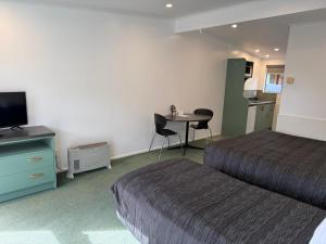 a hotel room with two beds and a table with a television at A'La Vista Motel in Palmerston North