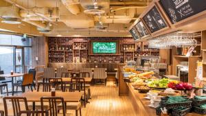 a restaurant with tables and chairs and a counter with food at HOTEL MYSTAYS Tachikawa in Tachikawa