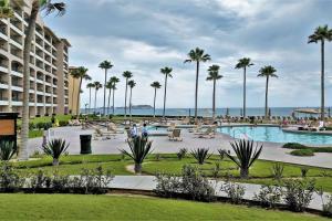 a resort with a pool and palm trees and the ocean at Sonoran Spa 304-N in Puerto Peñasco