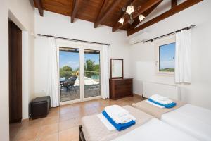 a bedroom with two beds and a balcony with a table at Villa Eudora in Tsoukalades +22 photos