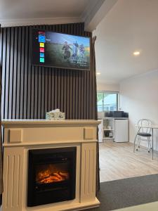 a living room with a fireplace with a flat screen tv at Bay Cottages in Kaikoura