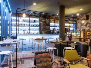 a restaurant with tables and chairs and a bar at Novotel Gent Centrum in Ghent