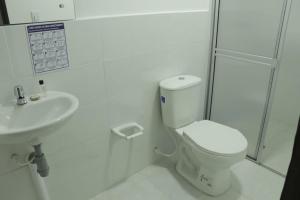 a white bathroom with a toilet and a sink at Hotel Inkanta in Nariño