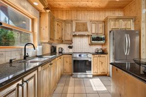 a kitchen with wooden cabinets and a stainless steel refrigerator at Fiddler Lake Resort - Deer 47 in Mille-Isles +24 photos