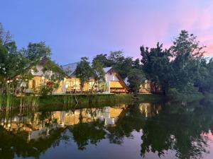a house on the river at dusk at Ban Mali Cafe & Riverside Stay in Ban Chang