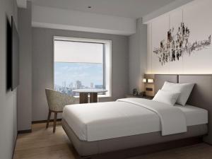 a bedroom with a bed and a table and a window at Hotel Crown Palais Kitakyushu in Kitakyushu