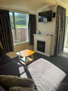 a living room with a couch and a tv and a fireplace at Bay Cottages in Kaikoura
