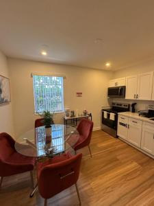 a kitchen with a glass table and red chairs at Daphne's Tropical Oasis Boutique Hostel in Hallandale Beach