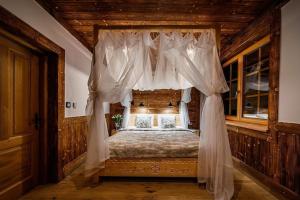 a bedroom with a canopy bed with white curtains at A large mountain-style house with a spa area in Murzasichle +33 photos
