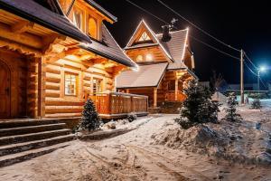 a log cabin in the snow at night at A large mountain-style house with a spa area in Murzasichle