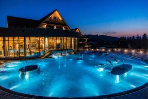 a large building with a large blue pool at night at A large mountain-style house with a spa area in Murzasichle