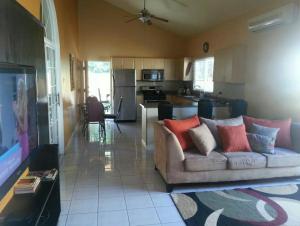 a living room with a couch and a kitchen at Caribbean Estate AJ in Portmore
