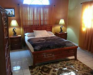 a bedroom with a bed with two night stands and two lamps at Caribbean Estate AJ in Portmore