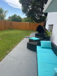 a patio with blue couches and a yard at Daphne's Tropical Oasis Boutique Hostel in Hallandale Beach