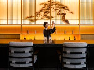 a woman standing in front of a table with two chairs at YOKI Matsushima in Matsushima