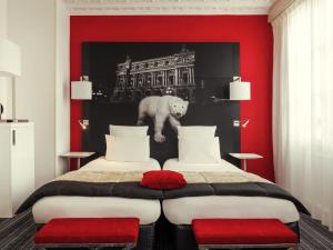 a bedroom with two beds and a red wall at Mercure Paris Opera Louvre in Paris