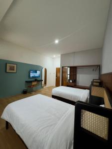 a hotel room with two beds and a flat screen tv at And Living Hotel in Kejayan +8 photos