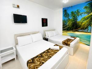 a room with two beds and a tv on the wall at Villa Adela Pension House in Balamban