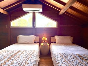 two beds in a attic room with a window at beau lac biwako annex in Takashima