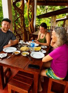 a group of people sitting at a table eating food at Sinharaja Forest Lodge - Deniyaya in Dombagoda +17 photos