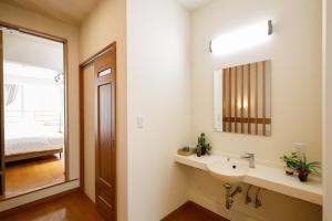 a bathroom with a sink and a mirror and a bed at 栞-shiori-NAKASONE in Miyako-jima