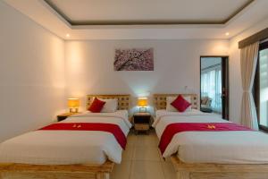 a bedroom with two beds and a painting on the wall at Villa Raka by Manara in Legian +160 photos