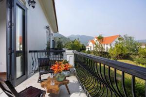 a balcony with two chairs and a table with flowers at Sunstone Villa in Trung Gia