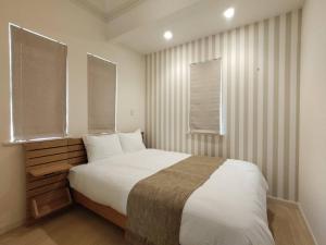 a bedroom with a large white bed with two windows at マークヴィラスイート in Shimo-suwa
