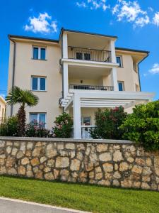 a tall white building with a stone wall at Family and pet friendly apartment Frankopan Croatia in Šmrika