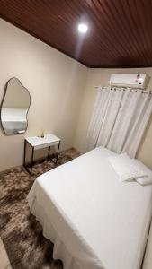a bedroom with a white bed and a mirror at Cantinho aconchego in Naviraí