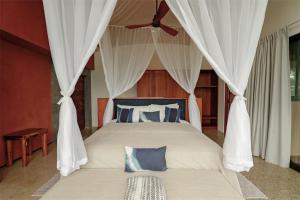 a bedroom with a large bed with a ceiling fan at Origins Astral in Bagaces