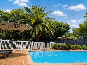 a pool with a white fence and a palm tree at Joy Haven - Cottage in Centurion