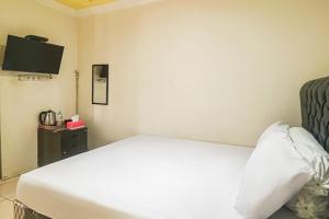 a bedroom with a bed and a tv on the wall at Kings Hotel Dieng RedPartner in Diyeng +31 photos