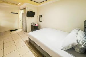 a bedroom with a white bed and a television at Kings Hotel Dieng RedPartner in Diyeng