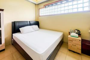 a bed in a room with a window and a table at Kings Hotel Dieng RedPartner in Diyeng