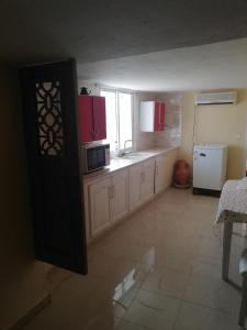 a kitchen with white cabinets and a microwave at Belle maison bord de mer rdc in El Haouaria