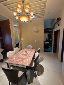 a dining room table with chairs and a chandelier at Sunita Kunj in Jhūsi