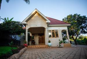 a small white house with a brick driveway at Panofu Homestay in Moshi