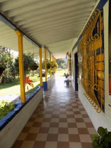 a hallway of a building with a tile floor and yellow columns at Posada La Loca Compañía in Salento