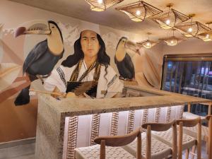 a woman standing behind a counter with a mural of birds at Casa Tayrona Suites in Medellín