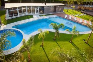 an overhead view of a swimming pool in a yard with palm trees at Hotel Posada Maestosso in Leones