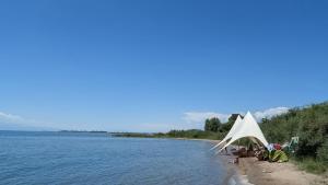 a white tent on a beach next to a body of water at Guest House of Issyk-Kul Camp in Chok-Tal