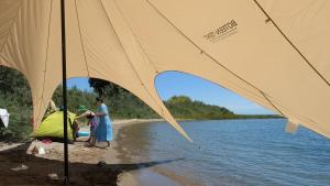 a woman standing on a beach with a tent at Guest House of Issyk-Kul Camp in Chok-Tal +8 photos