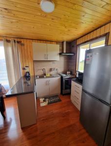 a kitchen with a stainless steel refrigerator and wooden ceilings at Cabañas Chiloé in Dalcahue