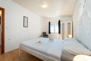 a white bedroom with a large bed with two pillows at My Dalmatia - Apartment Nostromo in Pag +38 photos