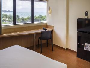 a room with a desk with a chair and a television at ibis Maceio Pajuçara in Maceió