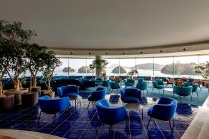 a lobby with blue chairs and tables and windows at Toba Grand Hotel in Toba