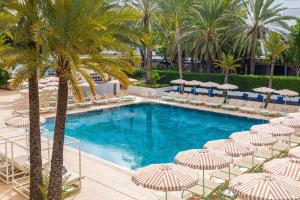 a swimming pool with umbrellas and chairs and palm trees at SOL by Meliá House Mallorca - Adults Only in Magaluf
