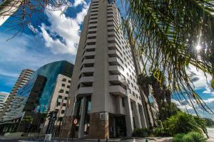 a tall building with a palm tree in front of it at Hotel Brasil 21 Convention, Affiliated by Meliá in Brasília