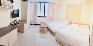 a bedroom with two beds and a desk and a television at 易民宿 Min su ji in Tainan